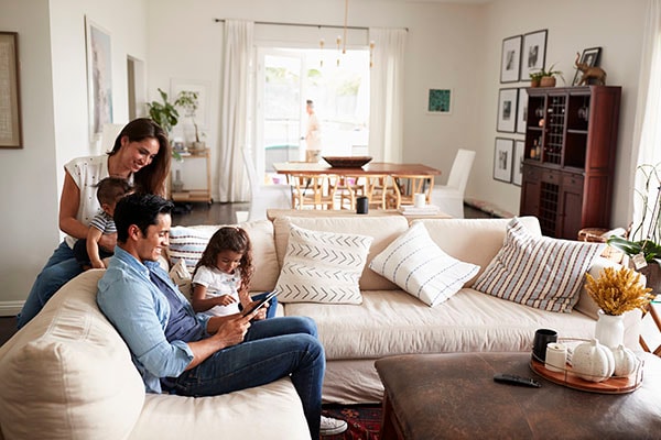 young family sitting on sofa reading a book together in their living room